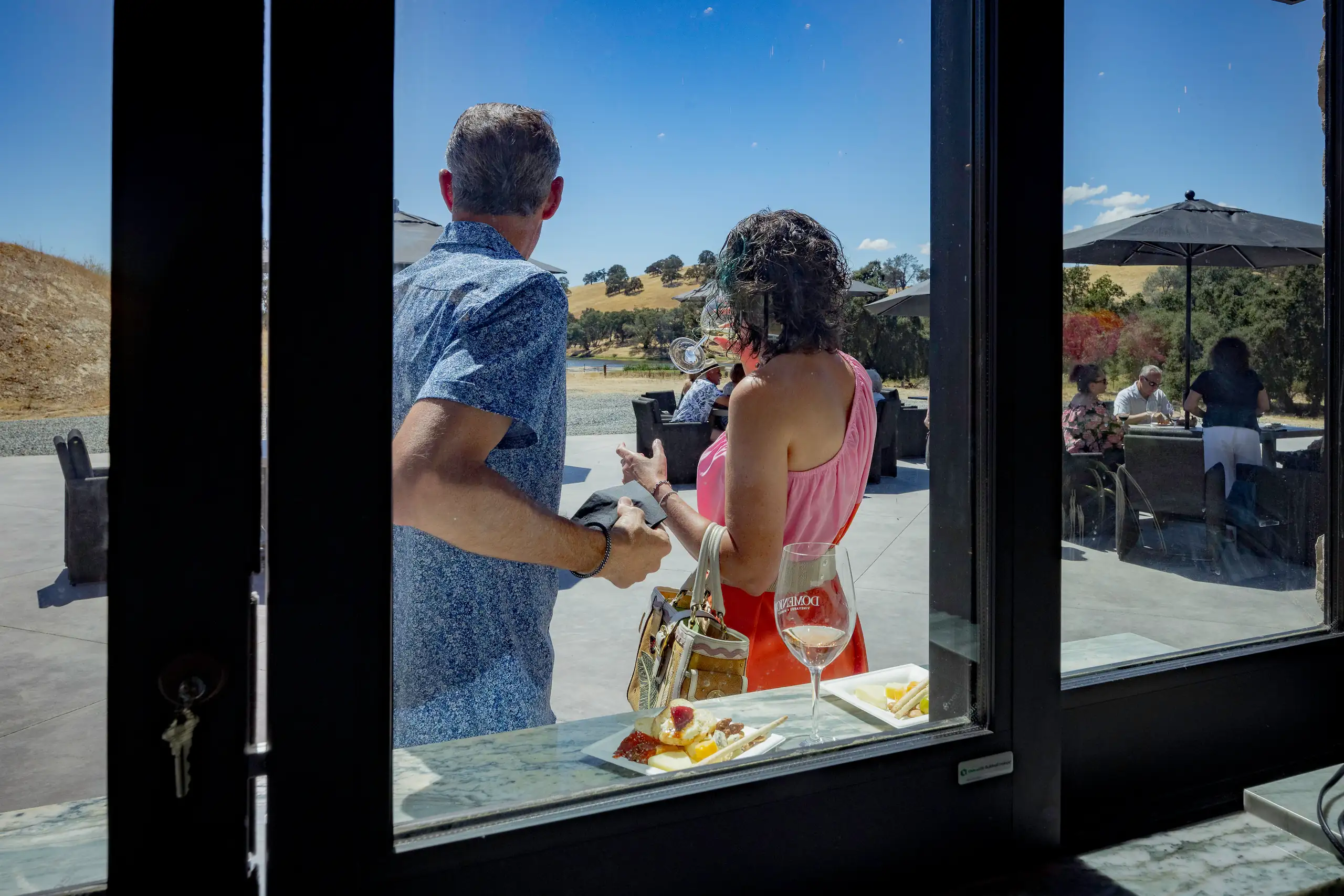 Two people enjoying wine at the Domenico Winery Amador back patio tasting room for Italian wine, event venue, with views of Sierra foothills.