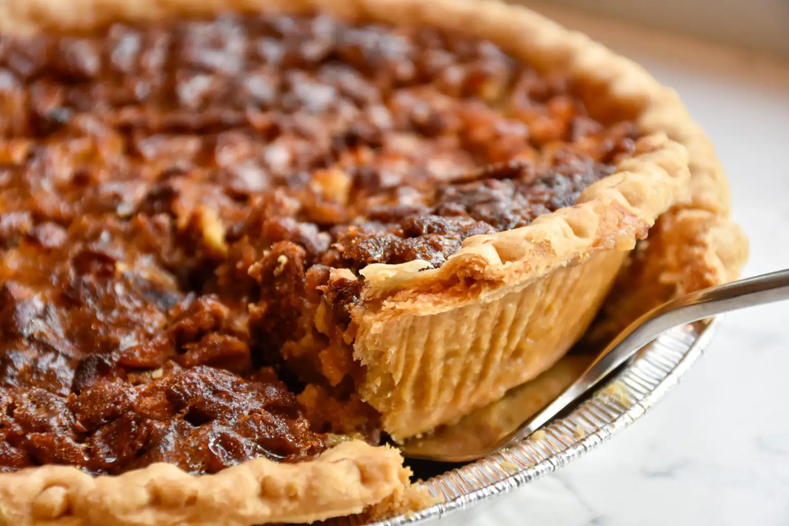 Close-up of a slice of pecan pie with a golden-brown crust and rich, gooey filling.