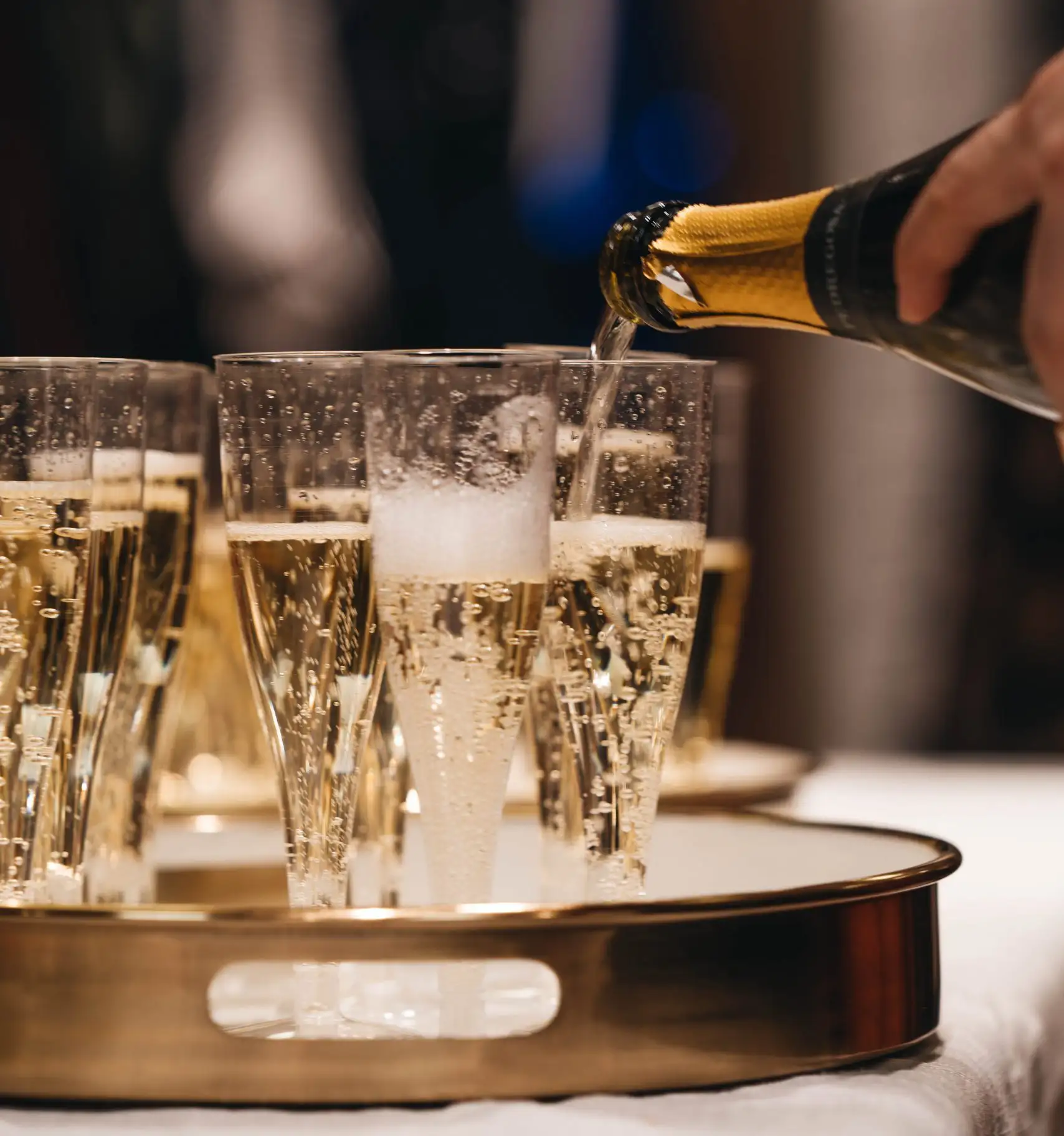 Champagne being poured into multiple glasses for a celebration with sparkling bubbles.