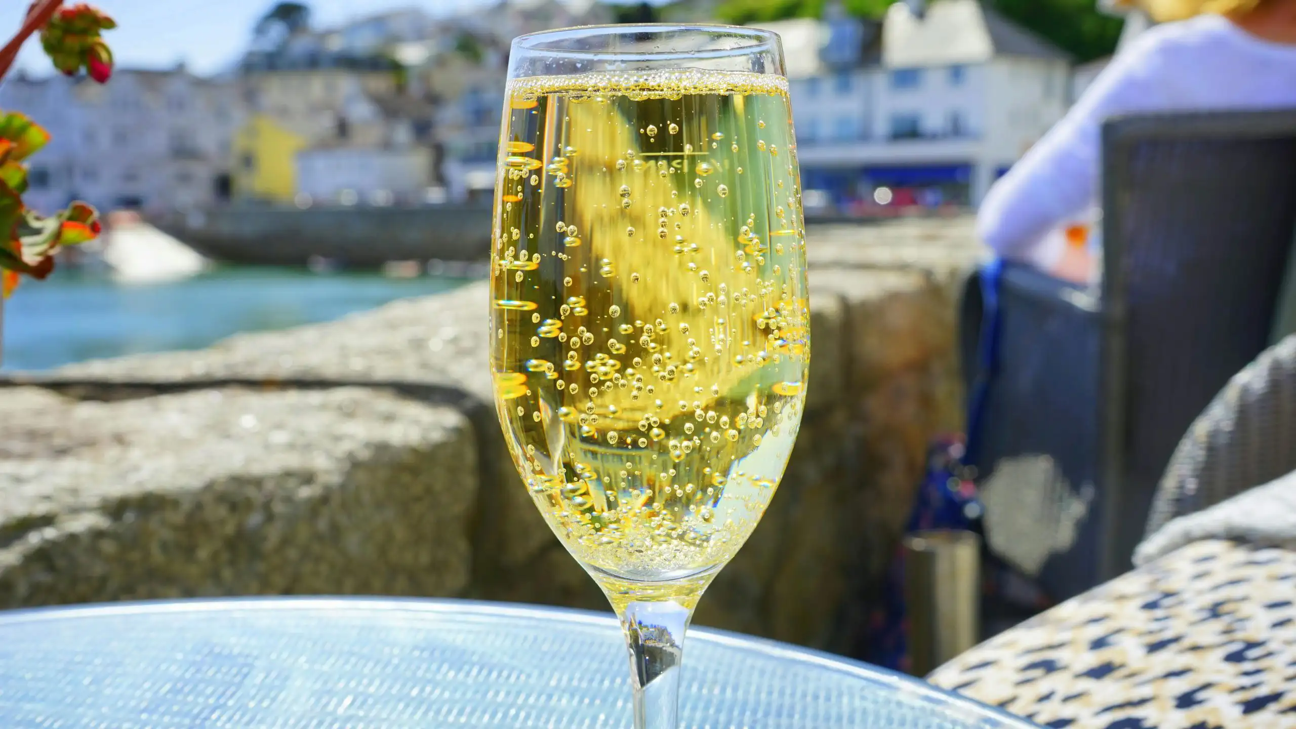 A glass of sparkling wine filled with bubbles, with a coastal town in the background.