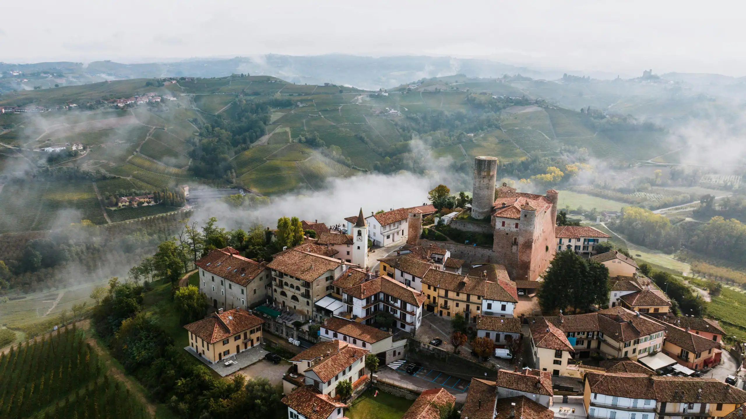 Aerial view of a vineyard town with fog rolling over hills.