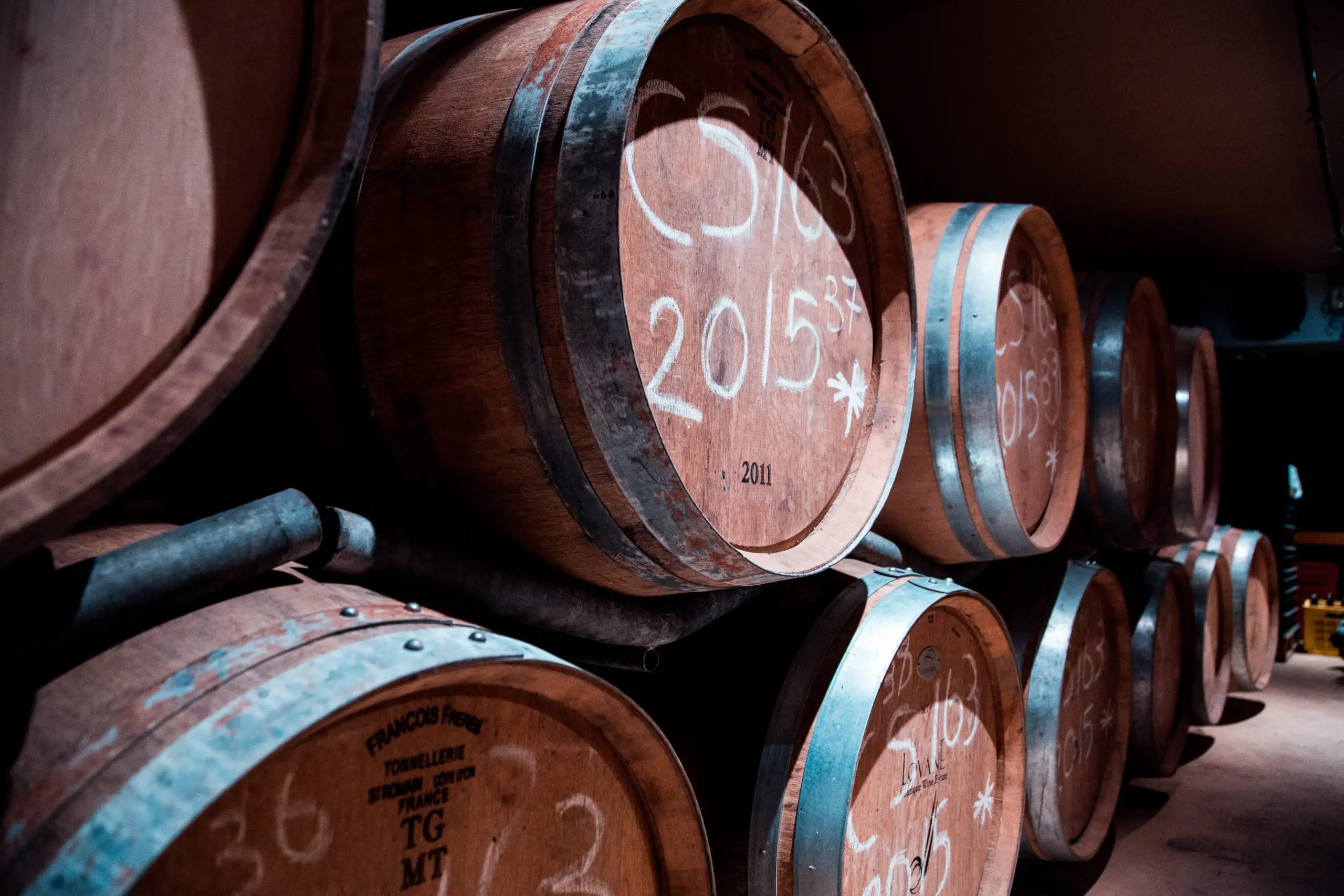 Wine barrels stacked in a dimly lit cellar with vintage markings