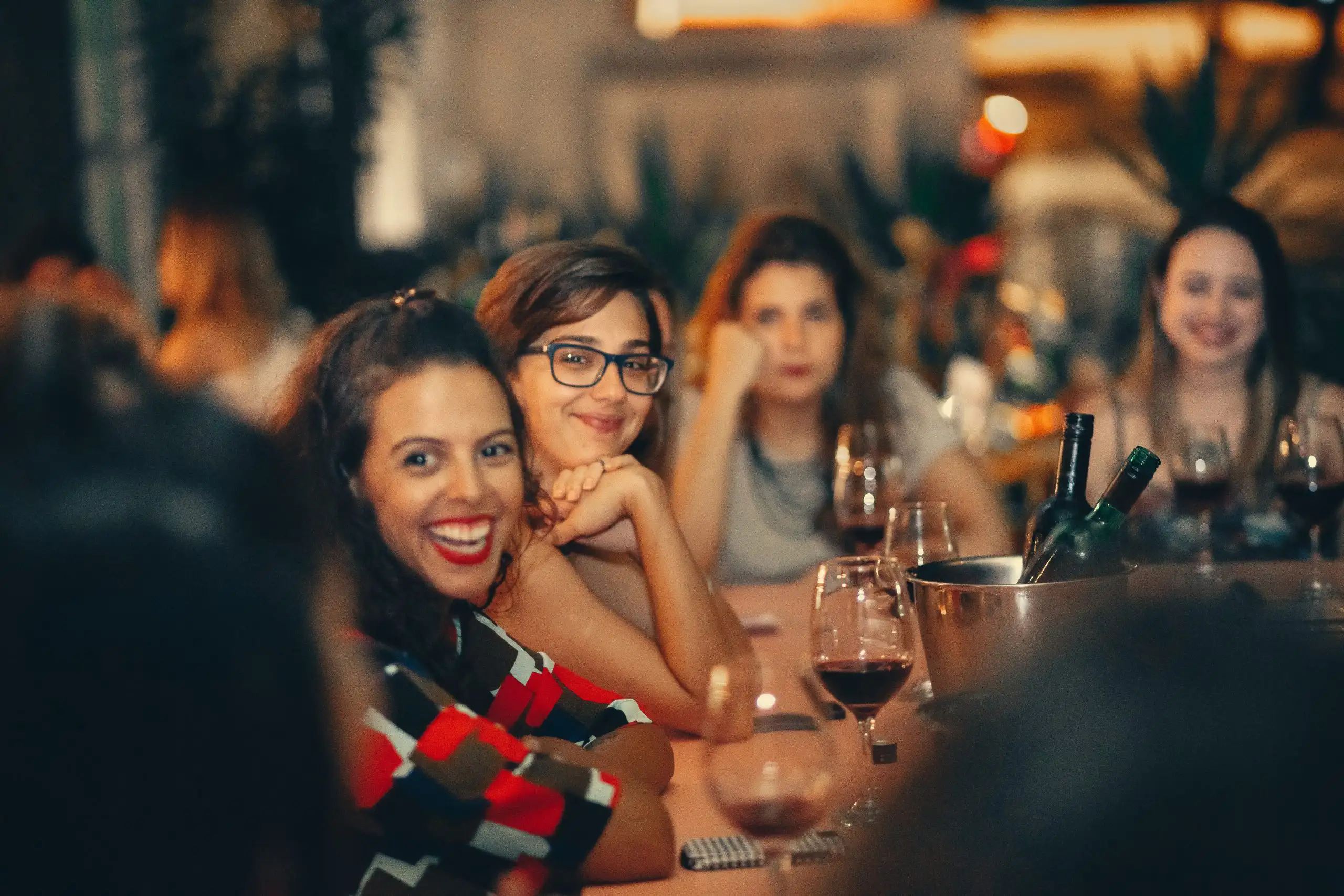 Group of women sitting together at a restaurant table enjoying wine and conversation.